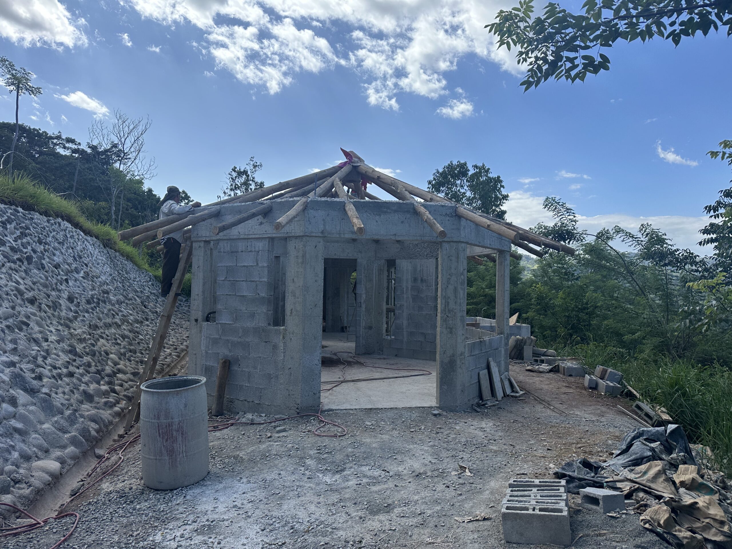 Masonry house with round timber roof rafters under construction in Puriscal