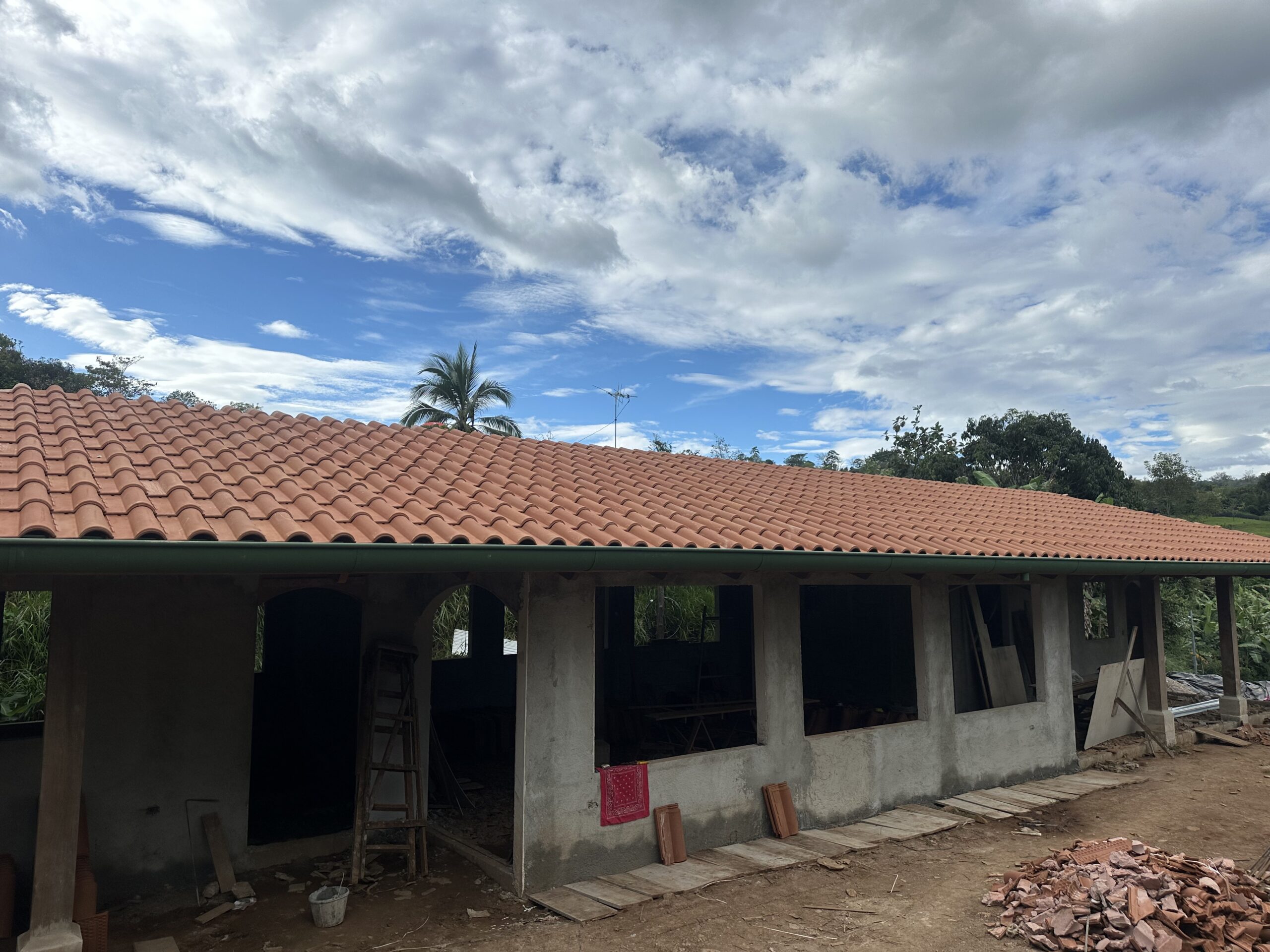 Wide clay-tile roof under construction beneath a dramatic sky