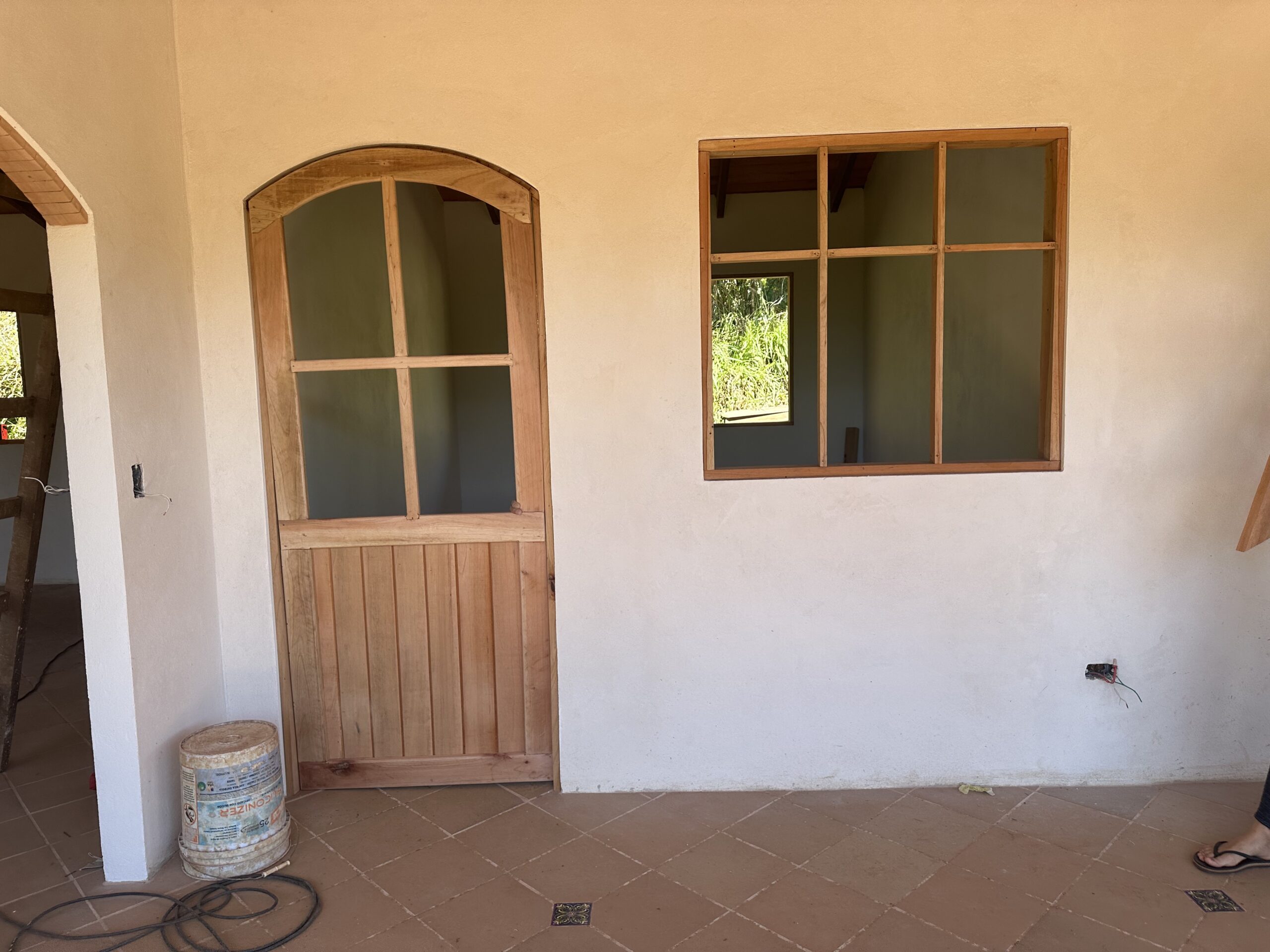 Handmade arched wooden door and timber-framed window during installation