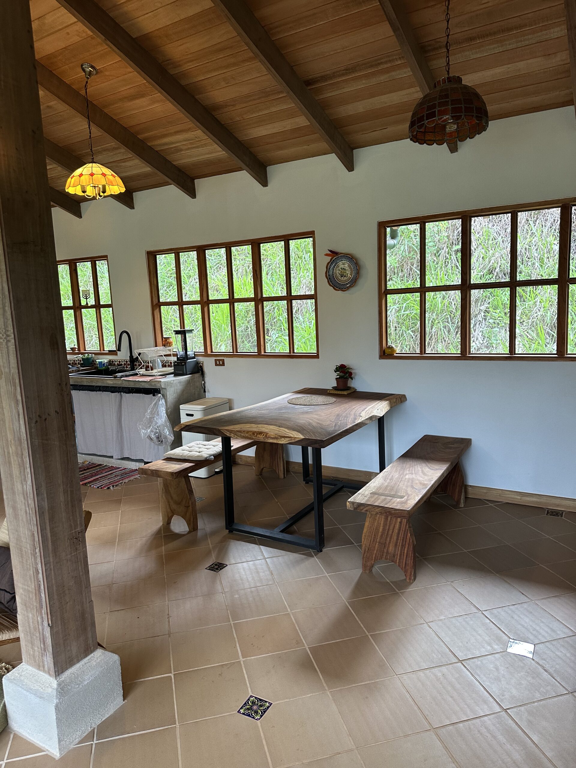 Dining area with handmade furniture and large timber-framed windows