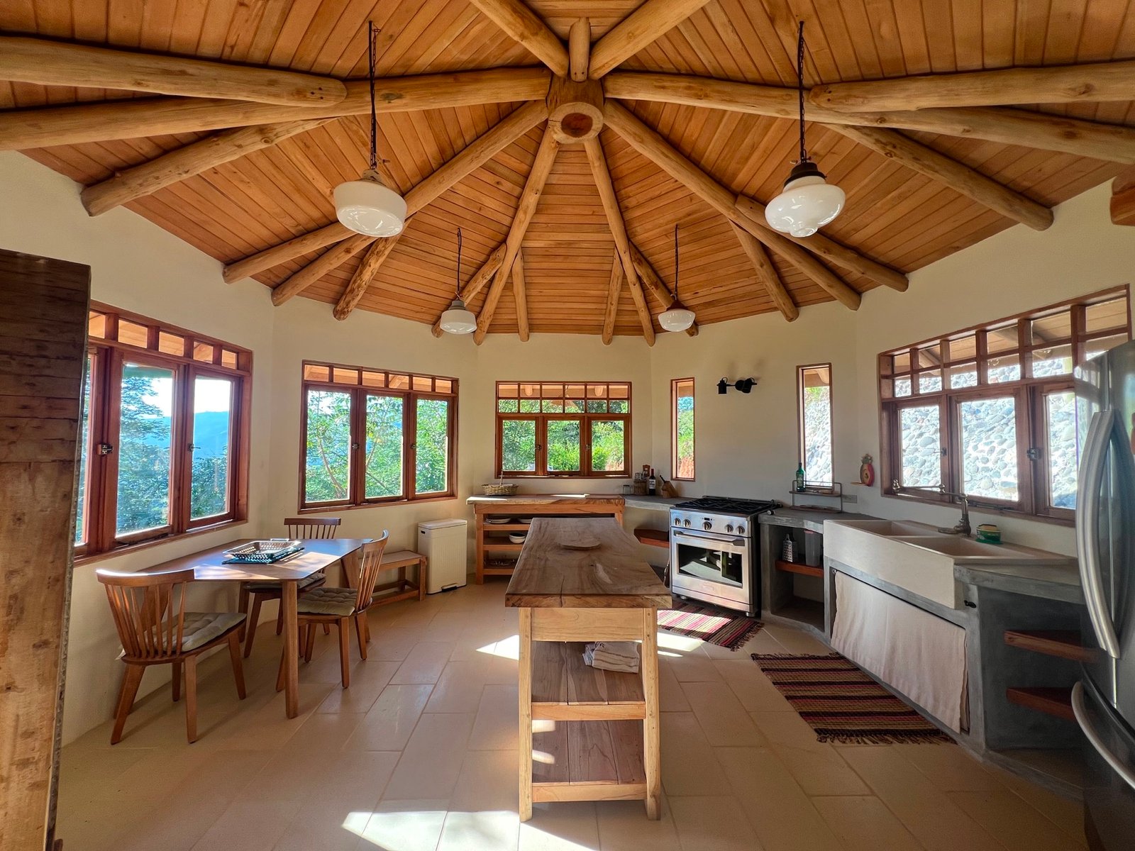 Completed kitchen and living space beneath a radial timber roof in Puriscal
