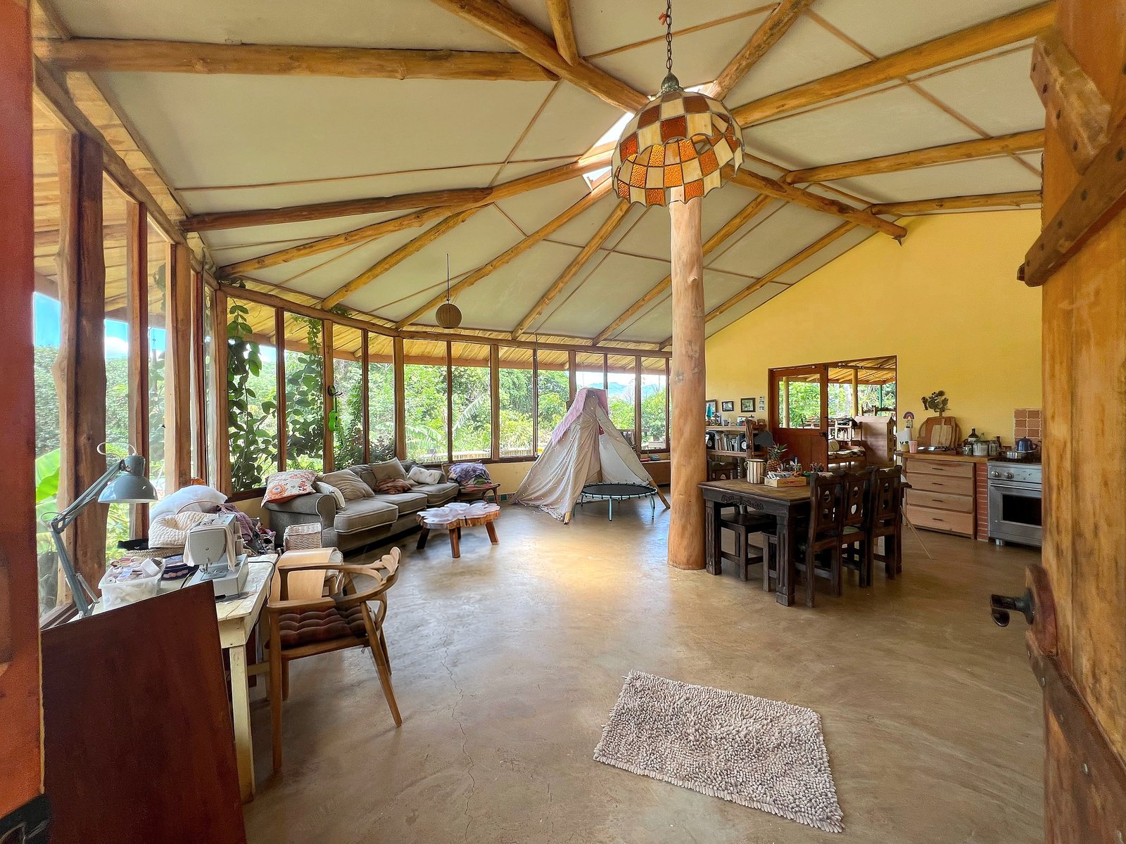 Open-plan living and dining space with round timber beams and garden views