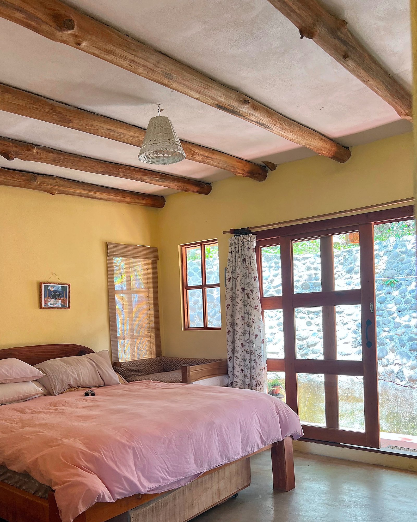 Bedroom with exposed round timber beams and timber-framed garden doors